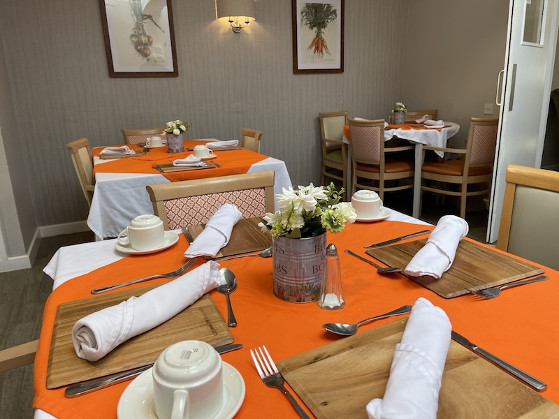dining tables with orange table cloths and utensils